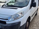 the white van is parked on the gravel road near a tree