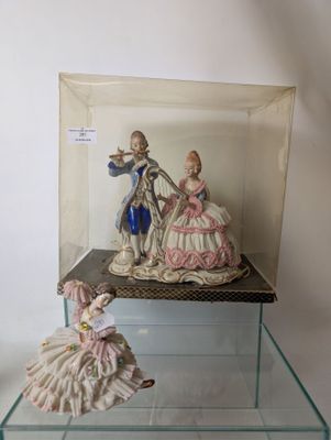 two figurines of people sitting on a glass shelf