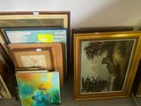de nombreux tableaux encadrés posés par terre dans une pièce