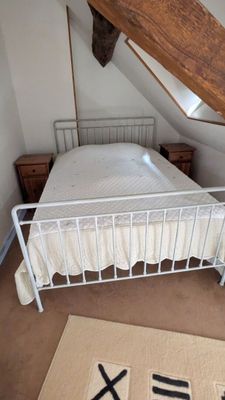 un lit blanc dans une chambre avec une poutre en bois au plafond