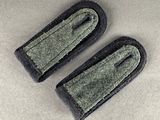 pair of black and grey military style patches on a gray surface