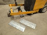 two pieces of metal on the ground next to a forklift