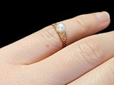 a woman ' s hand holding a ring with a pearl on it
