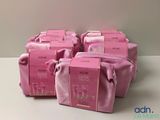 four bags of pink toiletries are lined up on a table