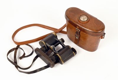 étui à appareil photo en cuir marron et jumelles sur fond blanc