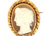Une broche plaquée or représente le profil d'une femme.