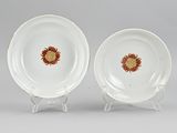 two white plates with orange flowers on them sitting on a stand