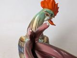 a figurine of a rooster sitting on a flower