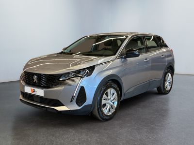Une voiture argentée est garée dans une pièce au sol noir.