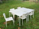 une table blanche et quatre chaises dans l'herbe