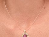 the woman is wearing a necklace that has a pink stone on it