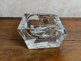 un bougeoir en verre transparent posé sur une table en bois