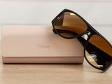 sunglasses and case on a wooden table with a white wall in the background