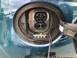 a close up of a blue car with an electric charger plugged into it