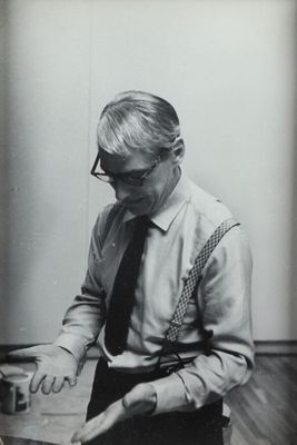 photographie en noir et blanc d'un homme en chemise et cravate en train de découper un morceau de papier