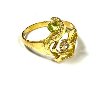 gold plated ring with green and white stones on top of a white surface