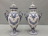 une paire de vases bleus et blancs posés sur une table, sur fond gris