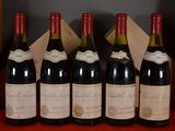 Six bouteilles de vin rouge sont alignées sur une table rouge.