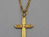 a gold cross pendant with a chain on a gray background