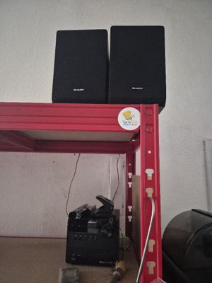 two speakers sitting on a red shelf next to a black bag