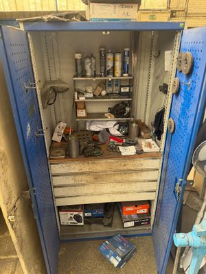 une armoire métallique bleue sur laquelle sont posés des outils, dans un garage