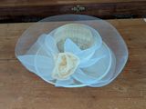 a white hat with a flower on it on a table