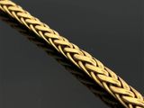 gros plan d'un bracelet en or sur une surface noire