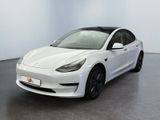 une Tesla Model 3 blanche garée dans une pièce blanche
