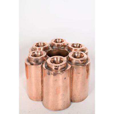 six vases en cuivre sont disposés en cercle sur une surface blanche