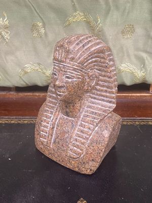 une statue en pierre représentant un pharaon assis sur une table noire