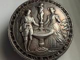 an old silver coin with a man and a woman playing a game of chess
