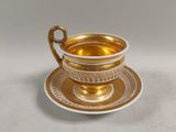 tasse et soucoupe dorées sur fond blanc