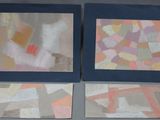 two framed paintings of different colors and shapes on a table