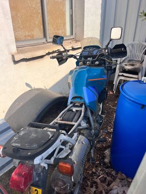 a motorcycle that is parked next to a blue barrel