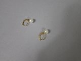 a pair of gold earrings with pearls on them sitting on top of a table