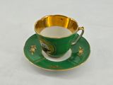 a green cup and saucer on a white table