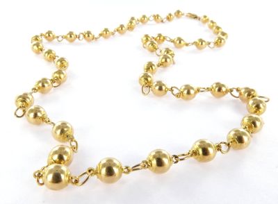 a close up of a gold beaded necklace on a white background