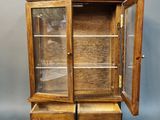 an old wooden display cabinet with two drawers and a glass door