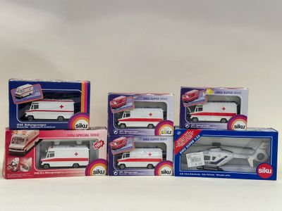 quatre boîtes contenant des ambulances miniatures, posées sur une surface blanche