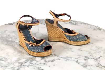 une paire de sandales à talons compensés Louis Vuitton posée sur une table en marbre