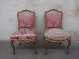pair of pink and gold chairs against a white wall in a room