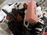 a pile of shoes and a pink box on a bed