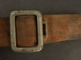 an old belt with a metal buckle on a gray surface