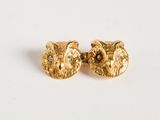 une photo d'une paire de boucles d'oreilles en forme de chouette en or posées sur une surface blanche