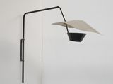 une lampe noire et blanche fixée au mur, d'où pend un morceau de papier