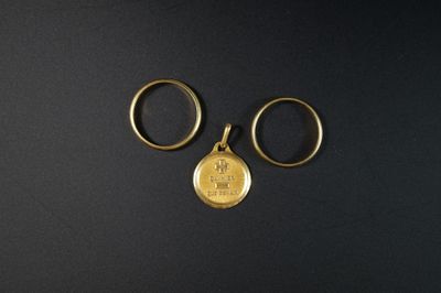 deux bagues en or et une pièce d'or sur un fond noir
