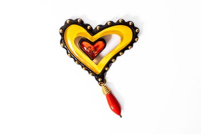 broche en forme de cœur jaune et rouge, avec une perle rouge qui pend