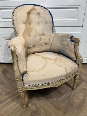 une vieille chaise dont la peinture s'écaille, posée sur un parquet