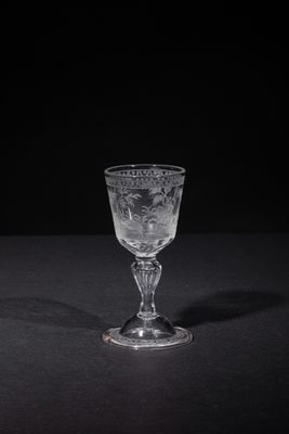 a wine glass sitting on a table with a black background