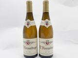 deux bouteilles de vin blanc posées l'une à côté de l'autre sur une surface blanche